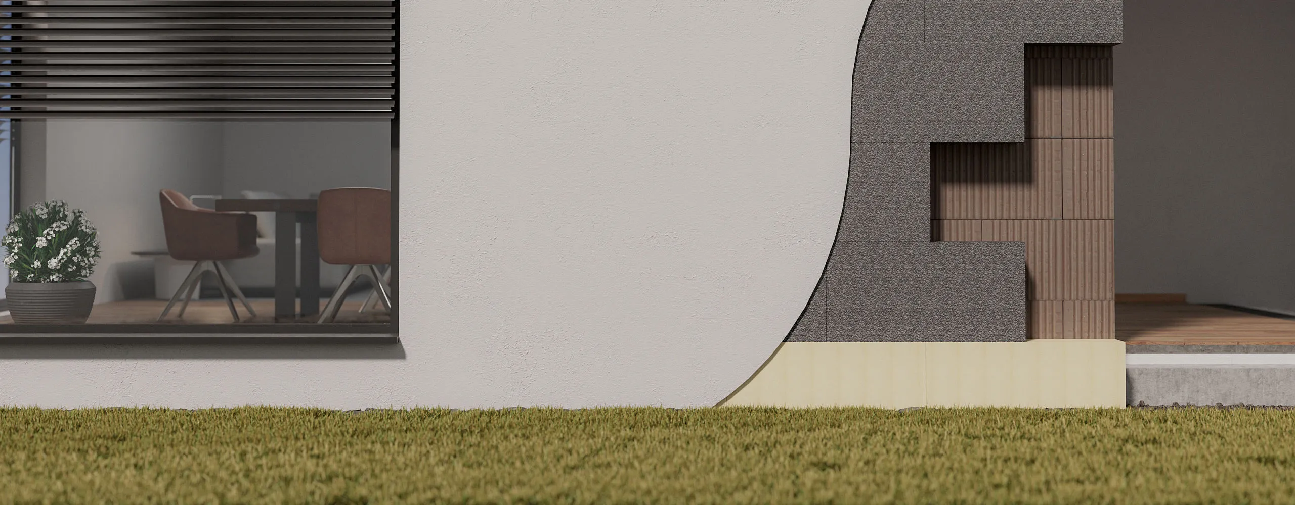 Hausfassade mit Dämmung und Fenster, das einen Tisch mit Stühlen im Innenraum zeigt. Vor der Fassade ist eine Rasenfläche.