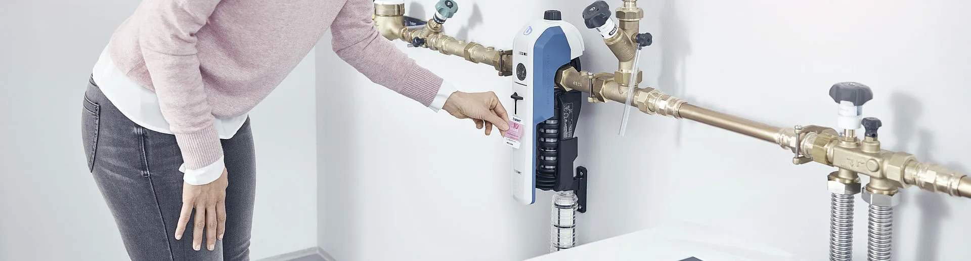 Eine Frau bedient einen modernen Trinkwasserfilter, der an einem Rohrleitungssystem montiert ist.