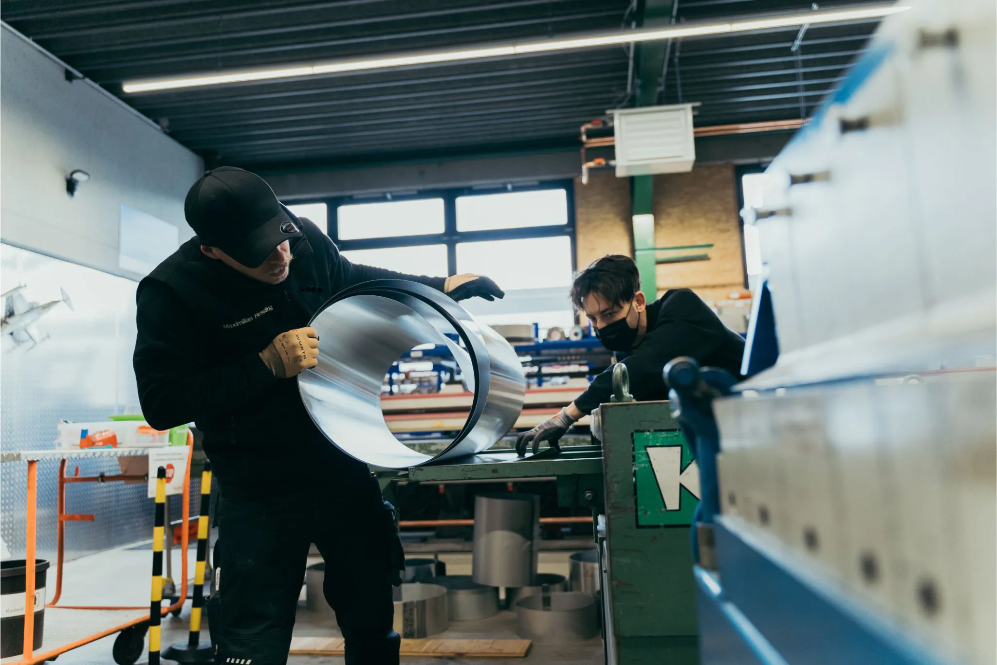 Zwei Flaschner bei der Metallarbeit in einem Arbeitsraum.