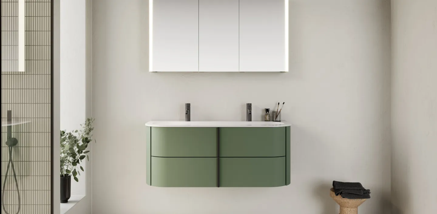 Ein modernes Badezimmer mit einem schwebenden, grünen Waschtisch, der mit einer weißen Oberfläche und zwei schlichten, schwarzen Armaturen ausgestattet ist.
