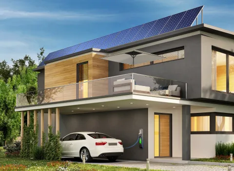 Elektroauto lädt an einer zweistöckigen Einfamilienhaus mit Wallbox und PV-Anlage. 