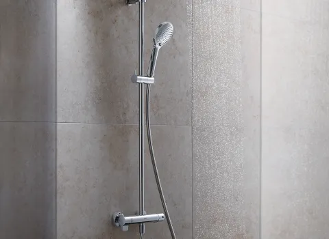 Ein Duschsystem mit glänzender Aufputzarmatur, bestehend aus einem Duschkopf und einem flexiblen Brauseschlauch, installiert an einer beigen Fliesenwand.