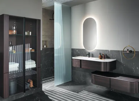 Luxuriöses Badezimmer mit dunklen Holzmöbeln, Glasvitrine und stilvoller Duschabtrennung.