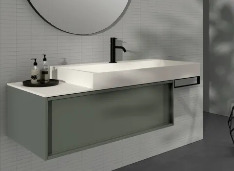 Modernes Badezimmerdesign von Stocco mit wandmontiertem Waschbecken in Weiß, grünlicher Unterschrankfront, rundem Spiegel und minimalistischer Dekoration.