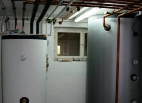 Mehrere Pufferspeicher mit Kupferverrohrung in einem Heizungsraum.