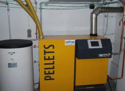 Pelletheizung mit Pelletkessel und Warmwasserspeicher im Heizungsraum.