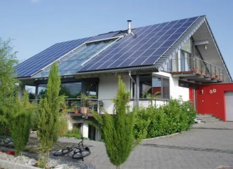 Einfamilienhaus mit Photovoltaikanlage und Solarkollektoren auf dem Dach.