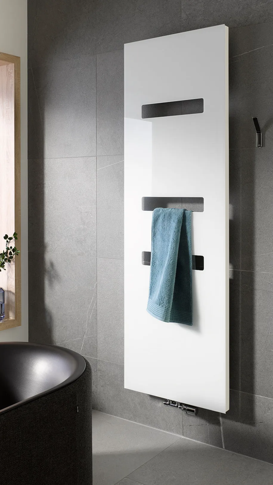 Ein stilvoller HSK Atelier Highline Heizkörper dominiert die Wand eines hochwertigen Badezimmers mit grauen Fliesen.