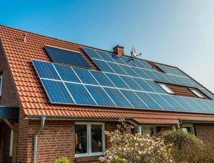 Backsteinhaus mit Photovoltaik und Solarthermie-Modulen auf dem Dach.